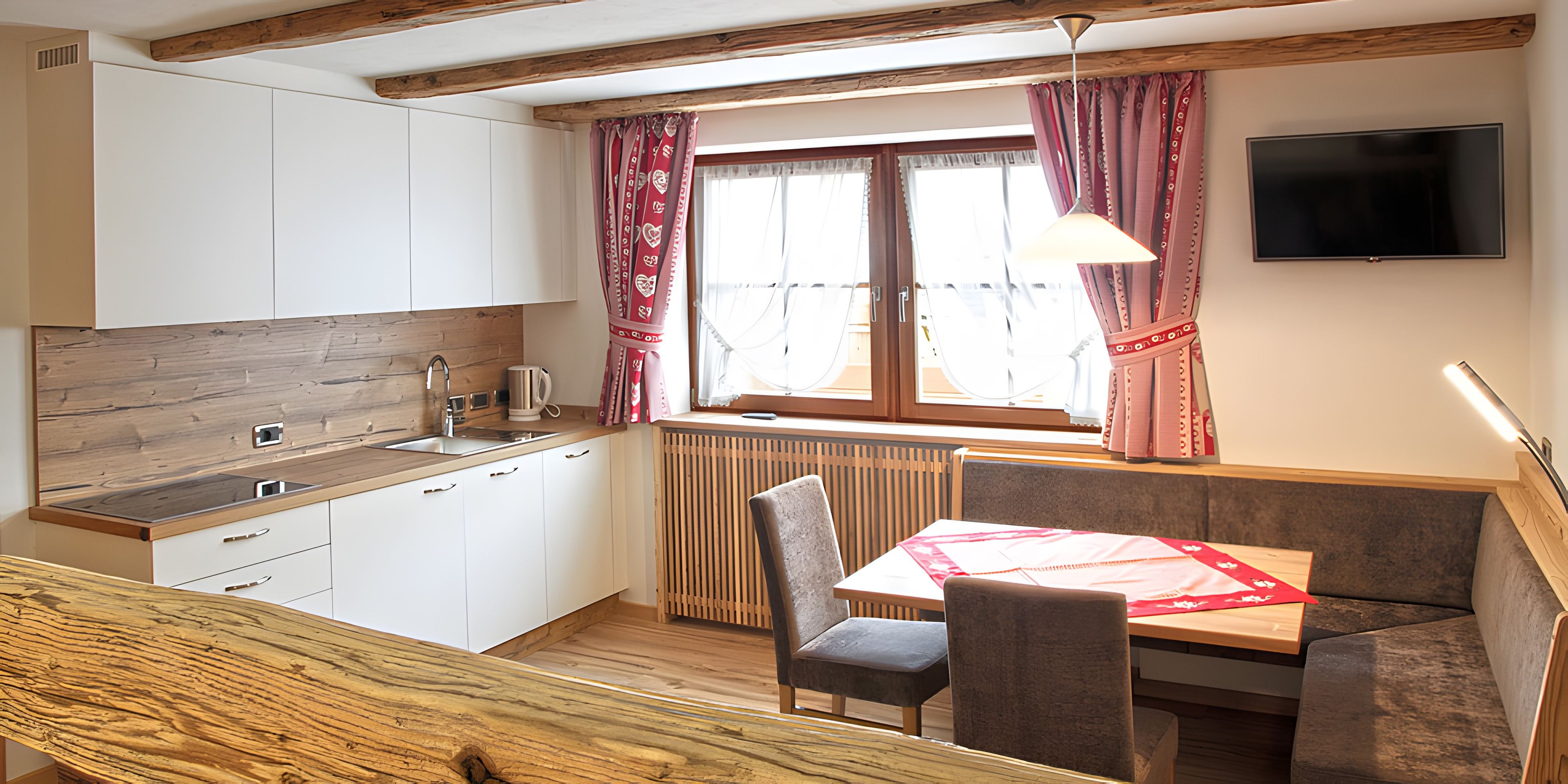A compact kitchen with a wooden countertop, a built-in sink, and a window with curtains.