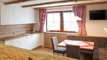 A compact kitchen with a wooden countertop, a built-in sink, and a window with curtains.