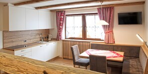 Cocina compacta con encimera de madera, pileta integrada y ventana con cortinas.