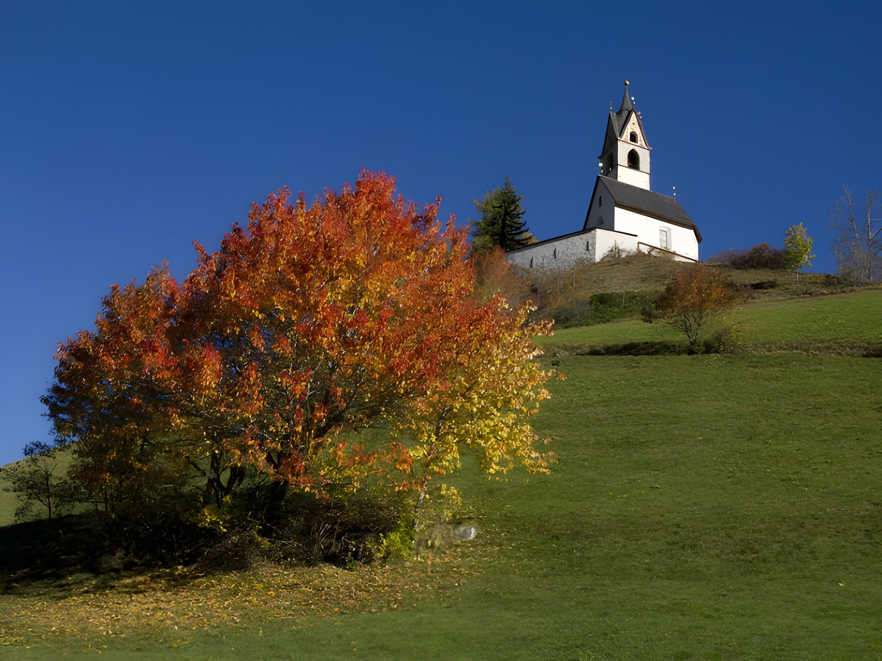 A church on a hill with autumn foliage.
