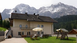 Un edificio a due piani con un balcone, posti a sedere all'aperto e vista sulle montagne innevate.