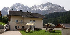 A two-story building with a balcony, outdoor seating, and a view of snow-capped mountains. - Apartment 'Wirthof  1' with Mountain View, Shared Terrace and Wi-Fi (La Valle)