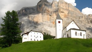 Una chiesa bianca con un campanile, sullo sfondo di una montagna.
