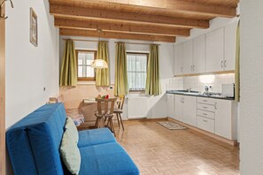 Ein gemütliches Wohnzimmer mit einem blauen Sofa und einer Essecke mit Tisch und Stühlen.