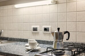 Eine Küchenarbeitsplatte mit Kaffeemaschine, Tasse und Löffel.