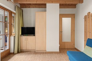 A room with a wooden ceiling, a television on a cabinet, a door, and a blue sofa. - Apartment 'Wirthof  3' with Mountain View, Shared Terrace and Wi-Fi (La Valle)