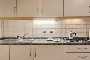 Una cocina con encimera de granito, pileta de acero inoxidable y cocina a gas.