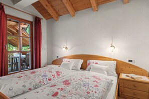 A bedroom with a wooden headboard, two bedside tables, a window with curtains, and a view of an outdoor area. - Apartment 'Wirthof  3' with Mountain View, Shared Terrace and Wi-Fi (La Valle)