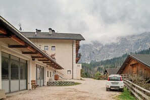 A mountain lodge with a dirt driveway, wooden exterior, and a view of the surrounding mountains. - Apartment 'Wirthof  4' with Mountain View, Shared Terrace and Wi-Fi (La Valle)