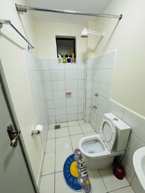 Ein Badezimmer mit Toilette, einer Duschkabine und einem kleinen Ablagefach für Pflegeprodukte.