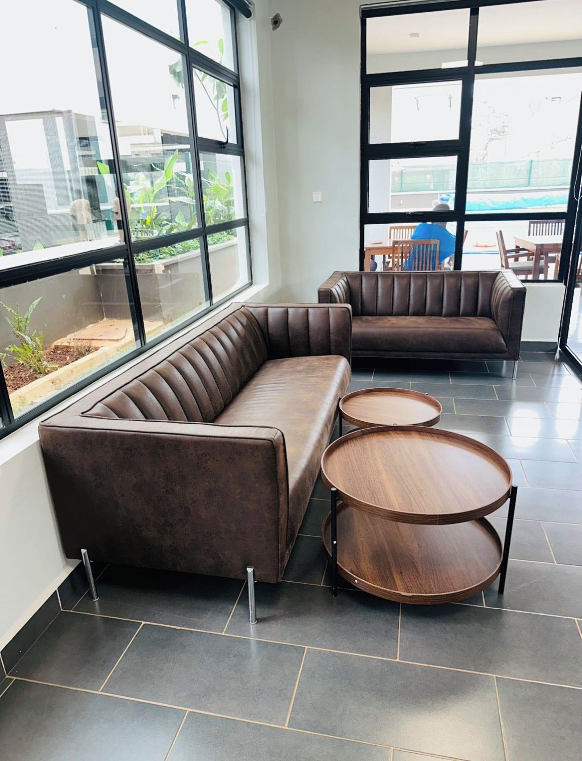 Un interior moderno con un sofá modular y dos mesas redondas de madera.
