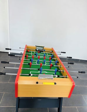 Una mesa de fútbol de mesa con base de madera y figuras de jugadores azules y rojos.