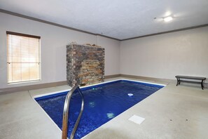 A room with a swimming pool, a bench, and a window with blinds. - Private indoor pool, driving sim games, pool table, Smoky Mountain views! (Gatlinburg)