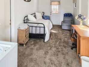 A bedroom with a bed, a wooden nightstand, a chair, a desk, and a door. - Lil Cottage - A Peaceful Country Retreat Near Yosemite and Sonora Pass (Jamestown)