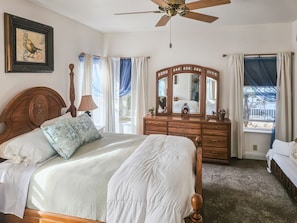 Ein Schlafzimmer mit Bett, Kommode, Spiegel und Deckenventilator.