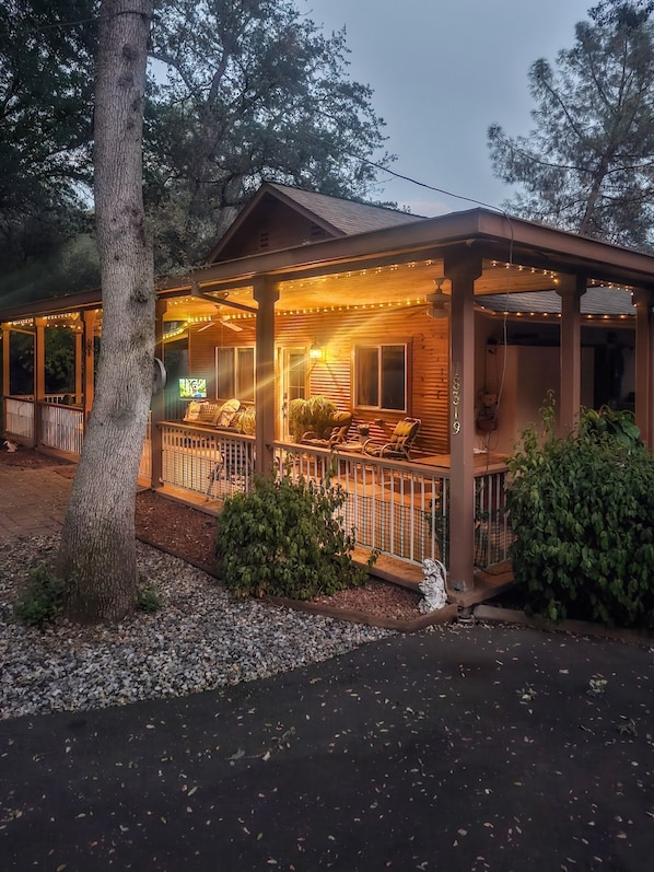 Eine Holzhütte mit Veranda, Lichterkette und einem kleinen Garten.