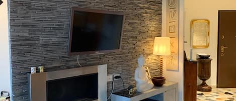 Ein modernes Wohnzimmer mit einer Steinwand, einem Flachbildfernseher, einem Kamin und einem Musterboden.