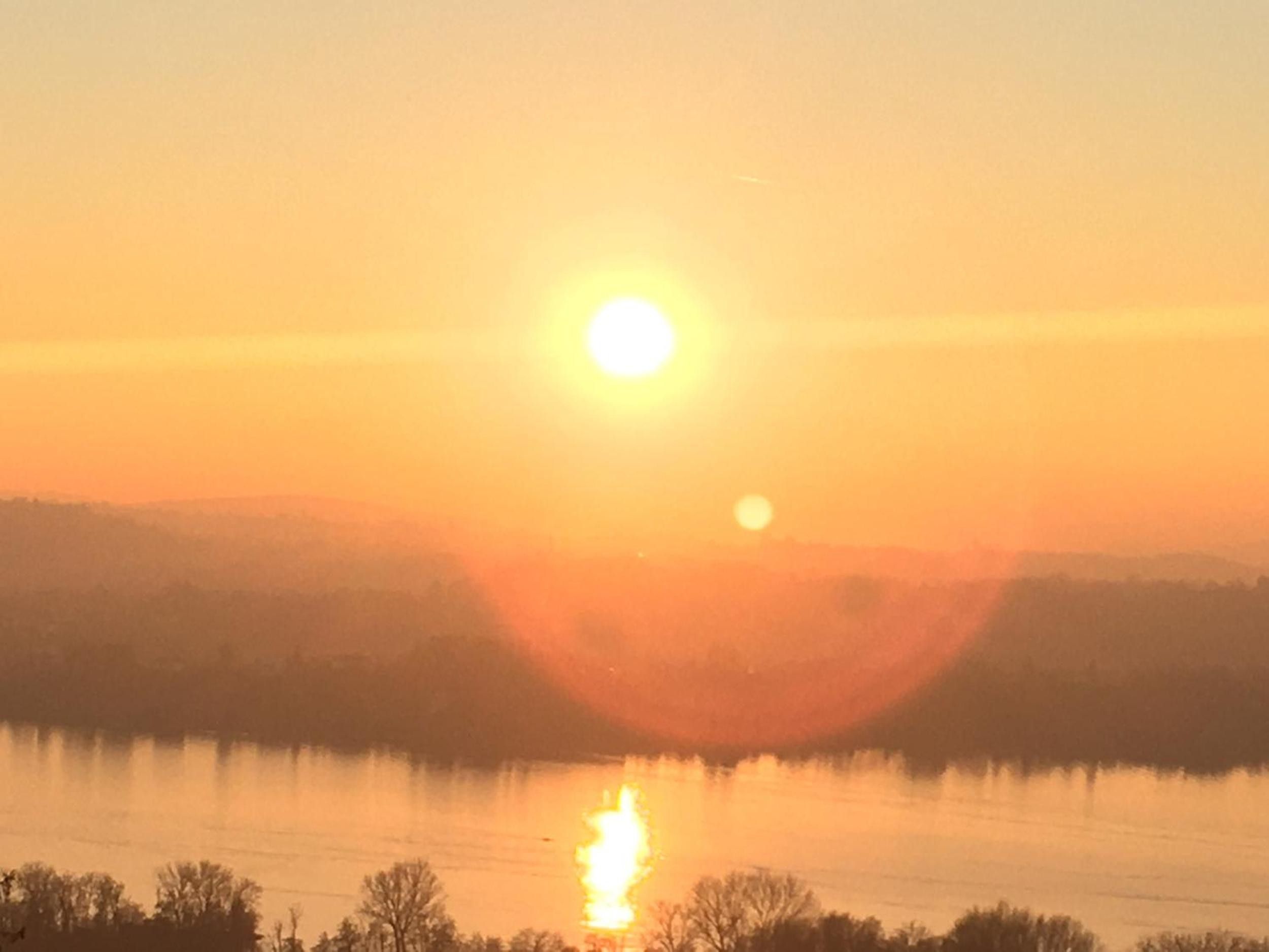A sunset over a body of water with a clear sky.