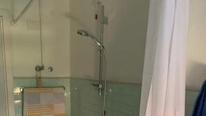 Casa de banho com banheira, chuveiro e porta-toalhas.