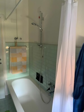 Un bagno con una vasca, una doccia e un porta asciugamani.