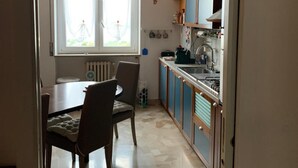 Cozinha com área de refeições, janela com cortinas e radiador.
