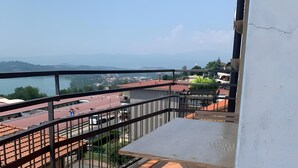 Een balkon met een tafel en stoel, met uitzicht op een stadslandschap en een wateroppervlak.