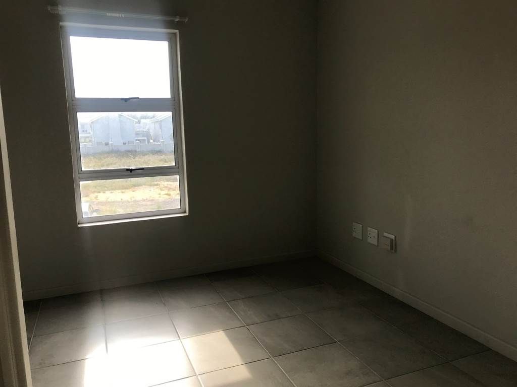 Ein Zimmer mit Fenster, Fliesenboden und Steckdosen an der Wand.