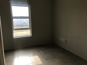 A room with a window, tiled floor, and electrical outlets on the wall.