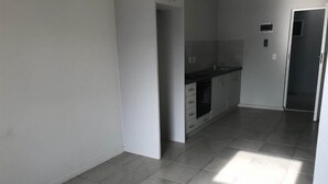 Una cocina con gabinetes grises, encimera negra y suelo de baldosas.