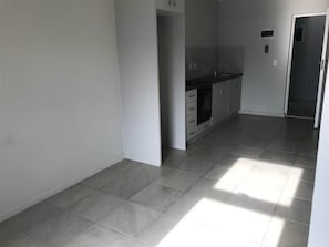 Una cocina con gabinetes grises, encimera negra y suelo de baldosas.
