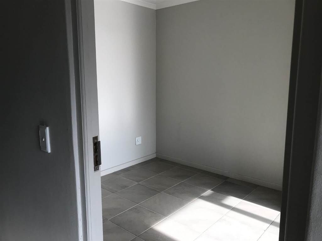 Una habitación con piso de baldosas, una puerta y un interruptor de luz en la pared.