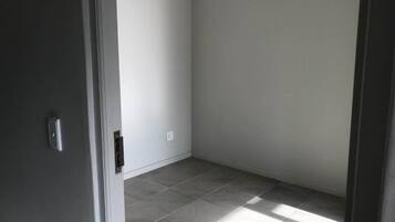 Una habitación con piso de baldosas, una puerta y un interruptor de luz en la pared.