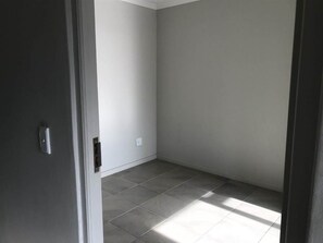 A room with a tiled floor, a door, and a light switch on the wall.
