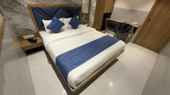 A modern hotel room with a large bed, a wooden headboard, and a marble wall.