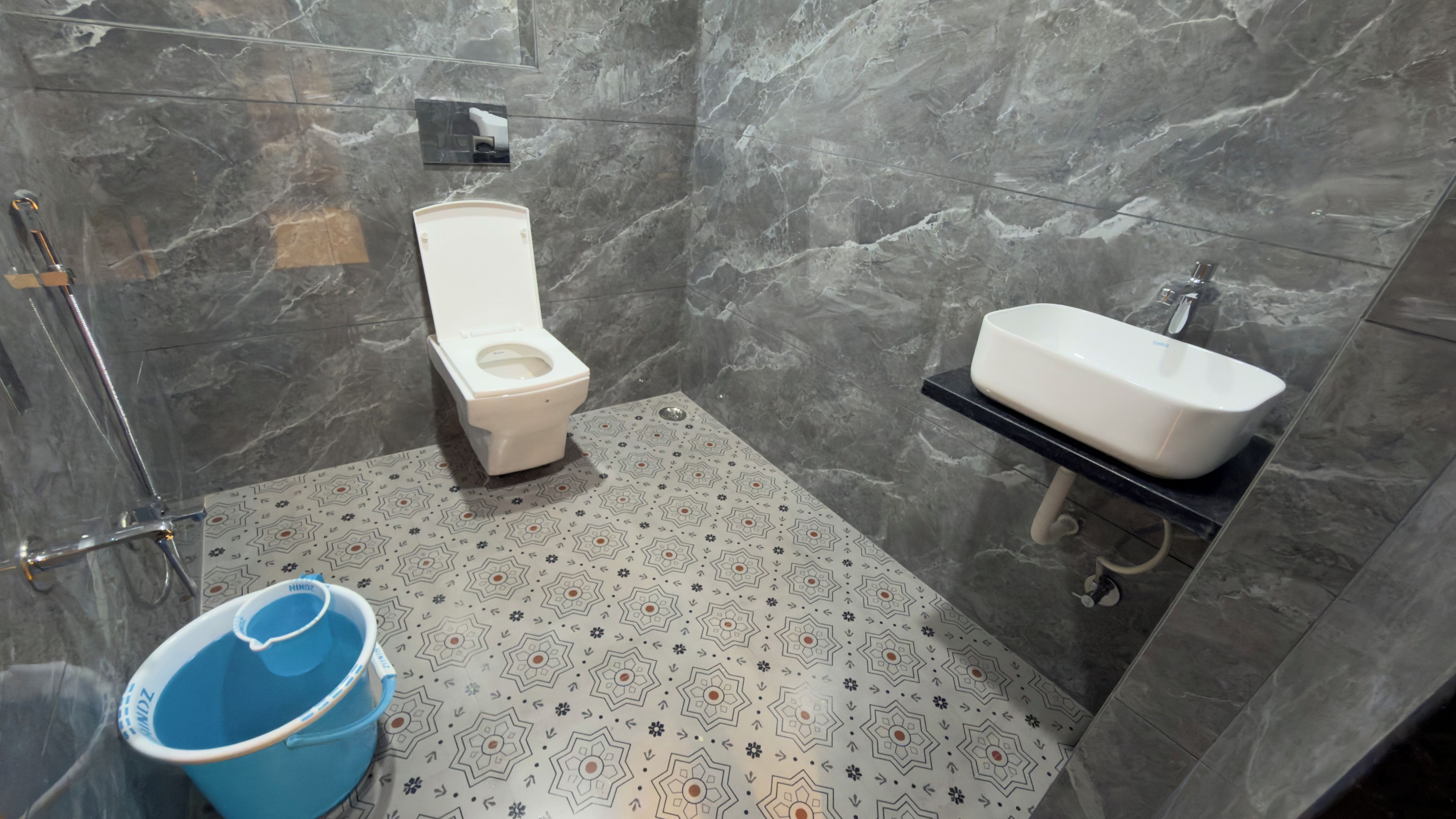 A bathroom with a toilet, sink, and patterned floor.