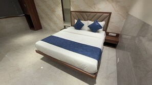 A modern bed with a wooden frame and a blue accent, set against a marble wall.