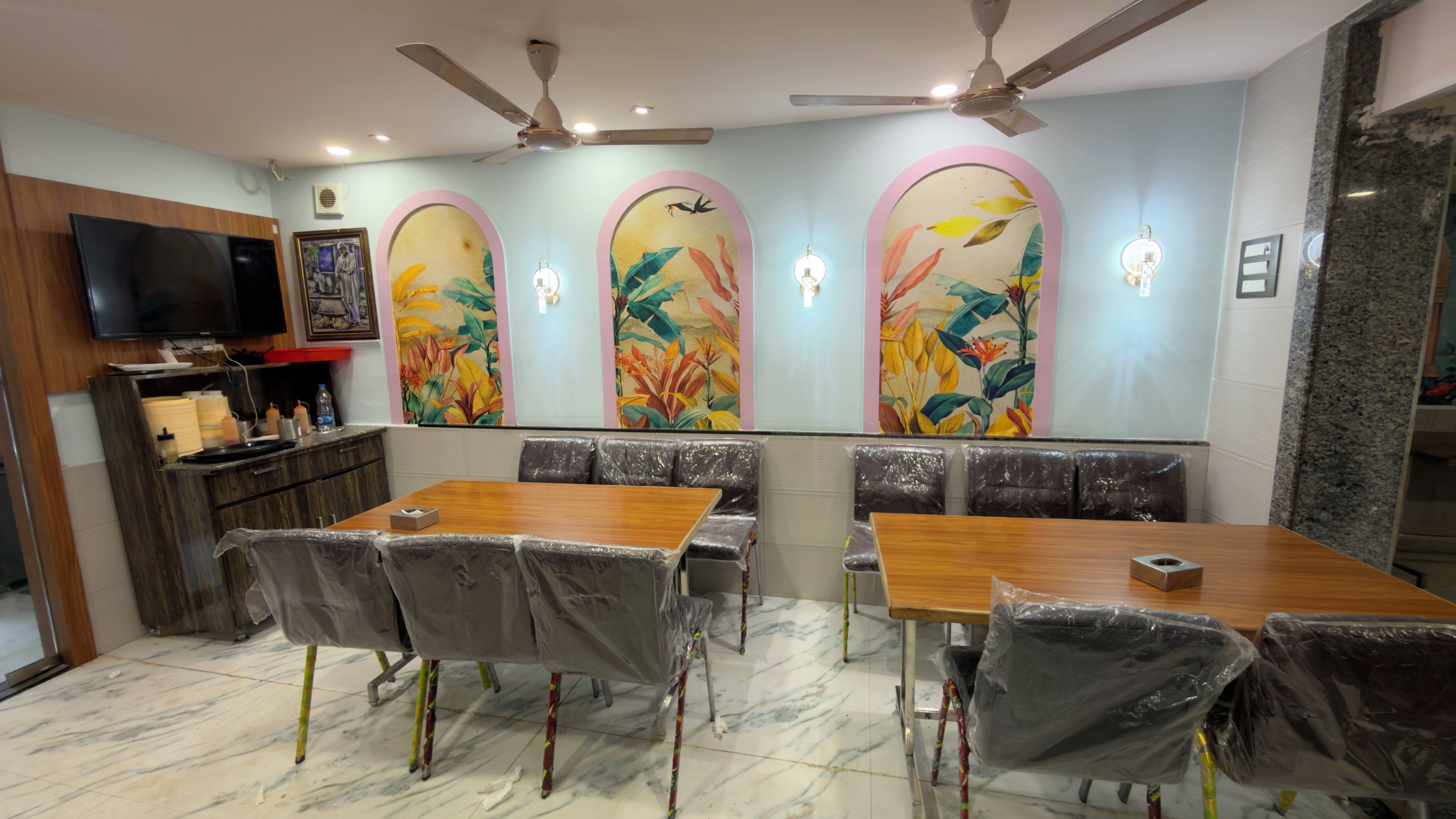 Un restaurante con una mesa y sillas de madera, un televisor y paneles decorativos en la pared.