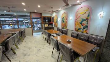 A restaurant interior with marble flooring, covered tables and chairs, and decorative wall art.