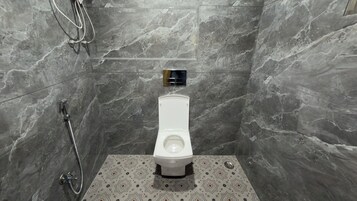 Un baño moderno con inodoro blanco, ducha y piso estampado.