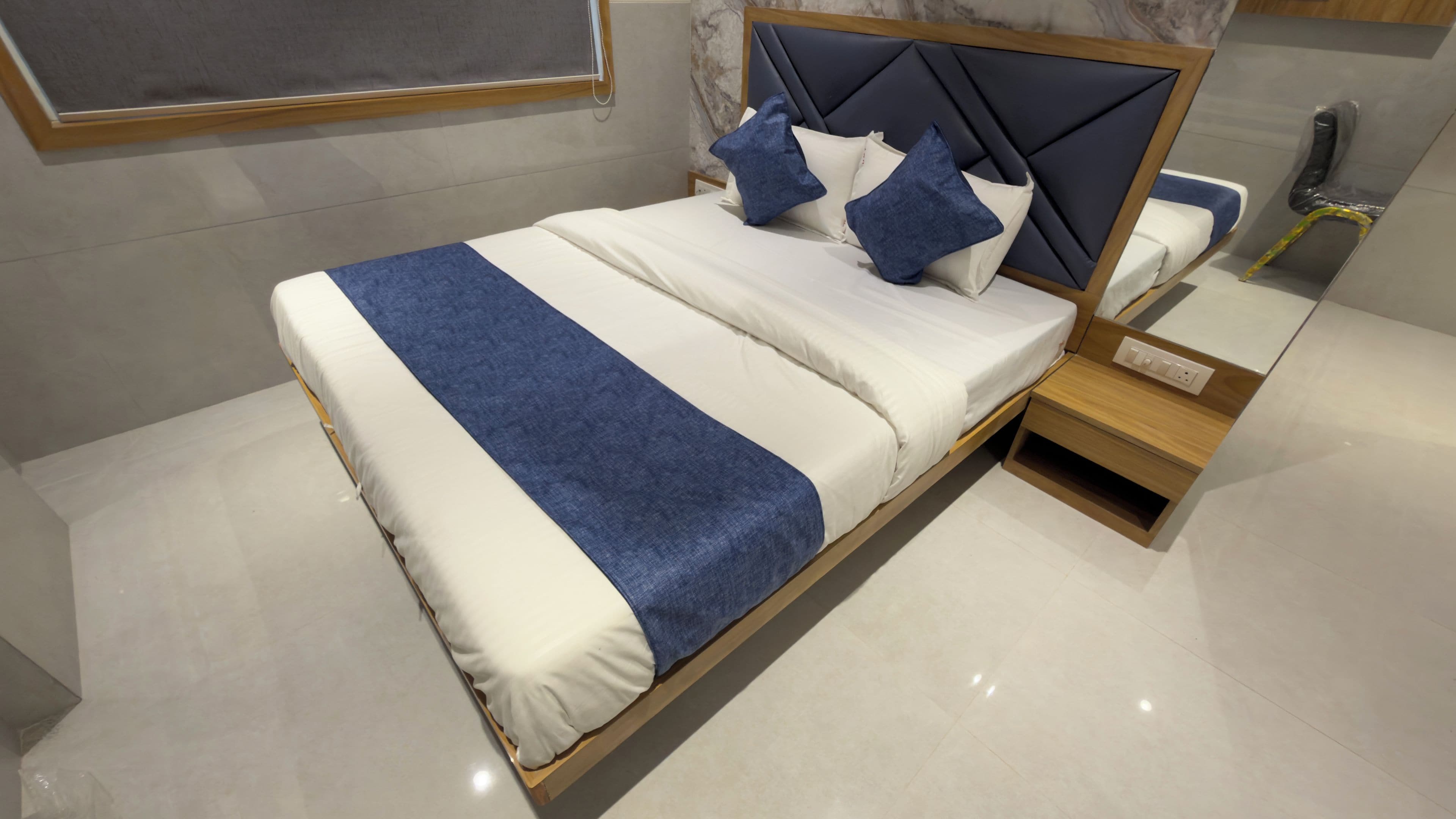 Una cama moderna con cabecera, mesita de noche y espejo.