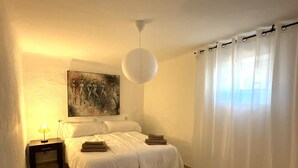 A bedroom with a bed, a nightstand, a lamp, a painting, and a curtain. - Spacious family home with 4 bedrooms and 2 terraces, just minutes from the A92 Autovia (Loja)