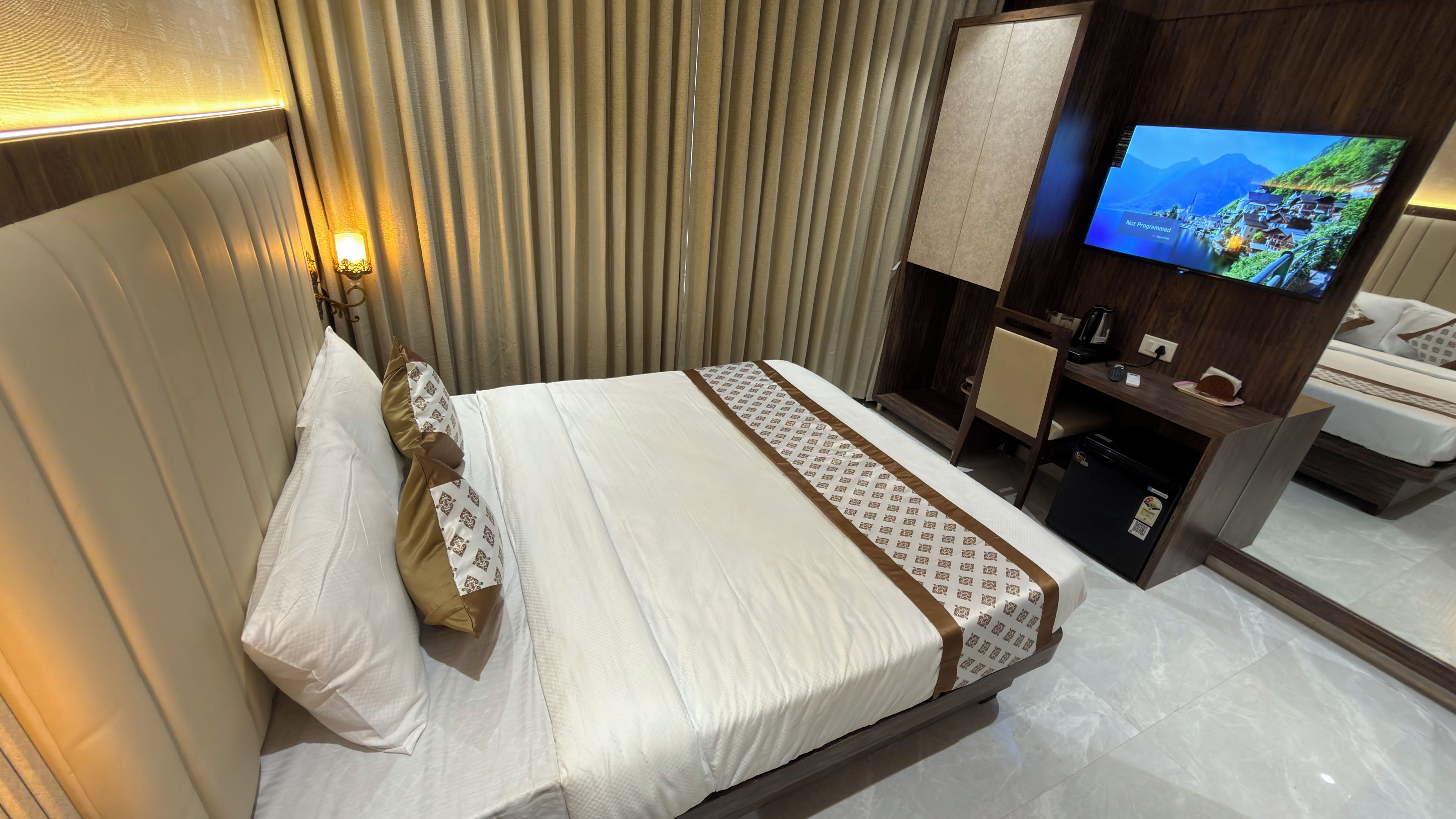 A hotel room with a bed, a television, a desk, and a coffee machine.