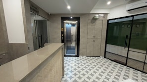 Un moderno vestíbulo de hotel con una recepción, un ascensor de vidrio y un piso estampado.
