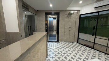 Un moderno vestíbulo de hotel con una recepción, un ascensor de vidrio y un piso estampado.