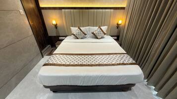 A hotel room with a large bed, two bedside lamps, and a headboard with vertical lines.