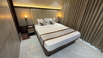 Habitación de hotel con una cama grande, dos lámparas de noche, una mesita de noche y una colcha estampada.