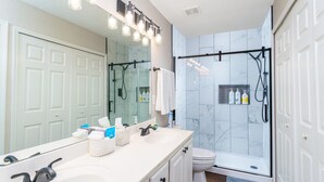 A bathroom with a white sink, a mirror, a shower, and a toilet. - Garden by the University (Charlotte)
