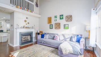 Una sala de estar con chimenea, un sofá, un tapete estampado y adornos en la pared.