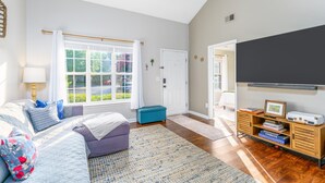A bedroom with a bed, a window, a door, a television, and a bookshelf. - Garden by the University (Charlotte)