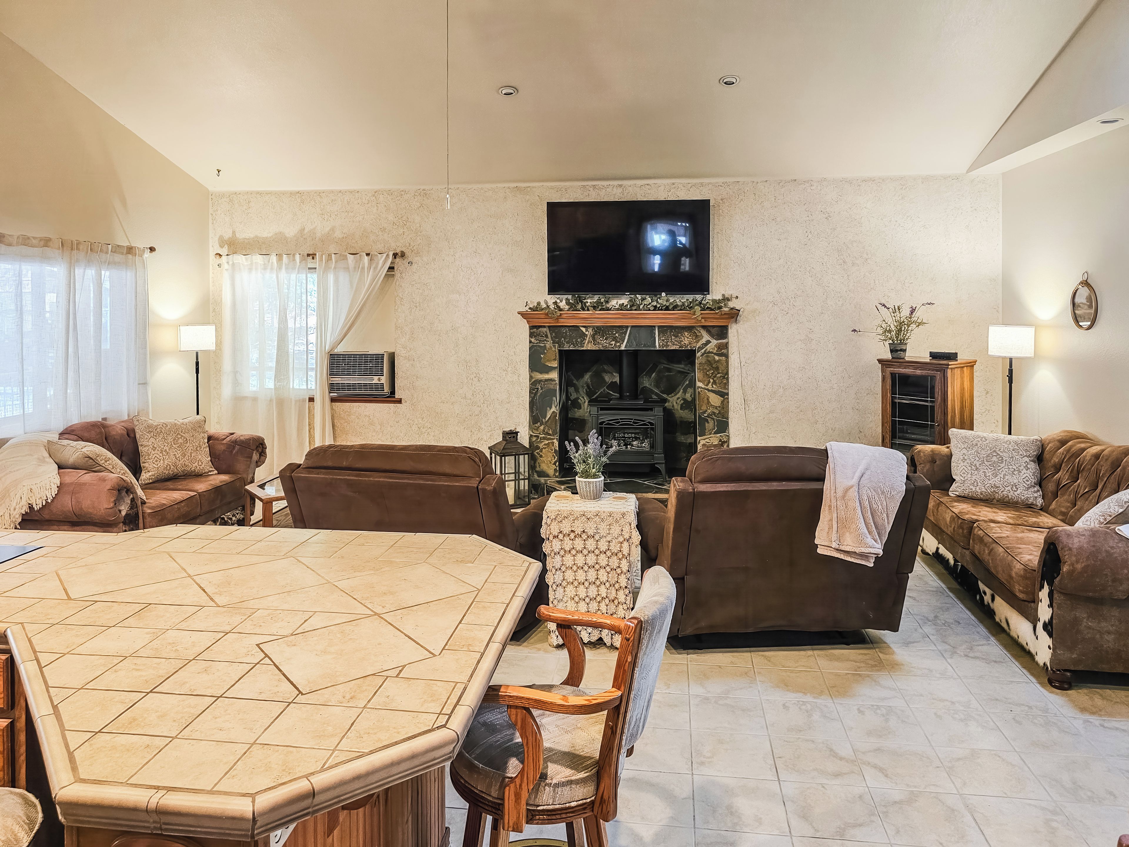 A living room with a fireplace, sofas, a TV, and a dining table.